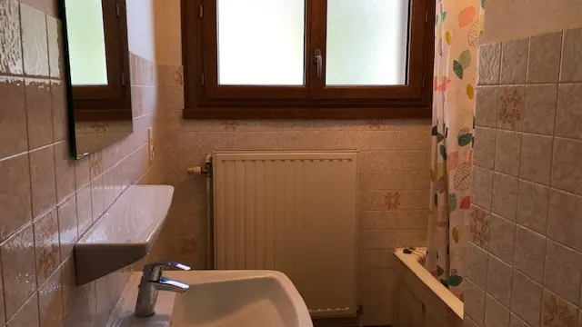 Salle de bain avec lavabo, baignoire et une fenêtre.