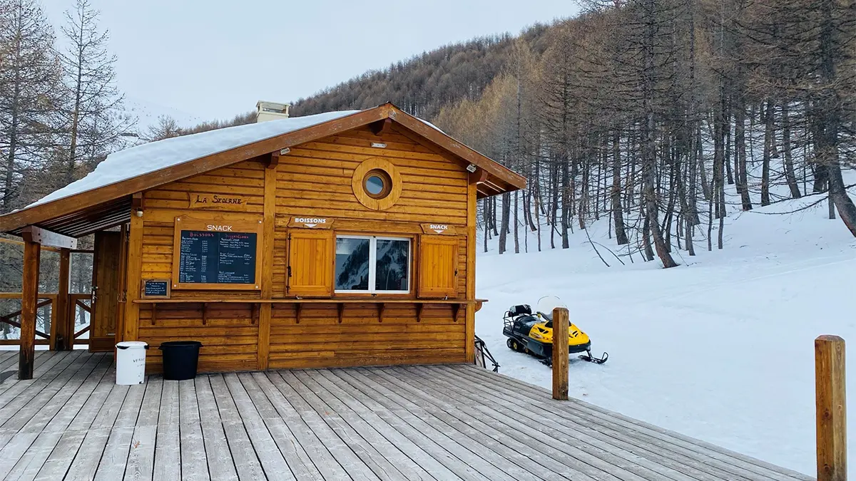 View from the restaurant's cabin, on its wooden deck. Snowy landscape and snowmobile