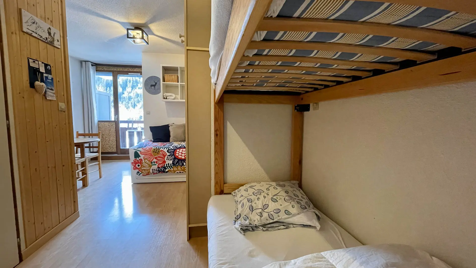 Entrée de l'appartement avec à droite le coin montagne et ses lits supperposées et vue sur la pièce à viver et le balcon