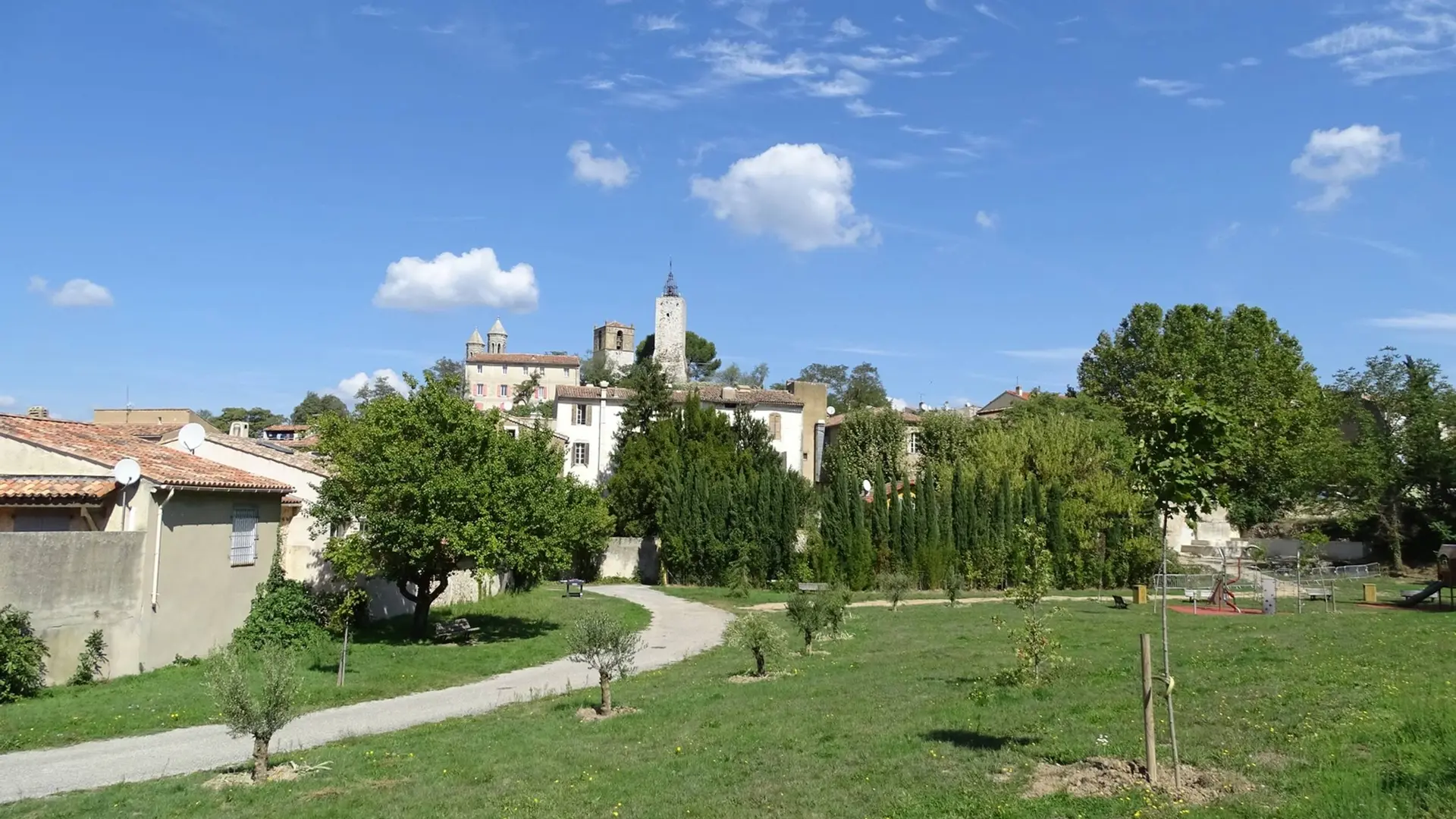 Vue sur le village avec son clocher en pierres et le parc arboré