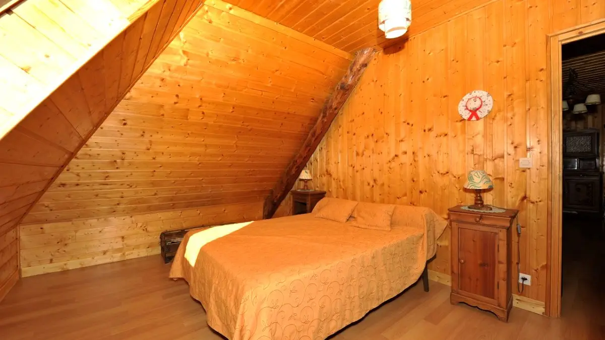 Bright bedroom in the attic, wood interior, double bed, wooden furniture, window