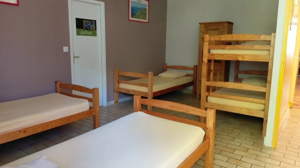 Dortoir de cinq couchages dans une grande chambre ouverte.
