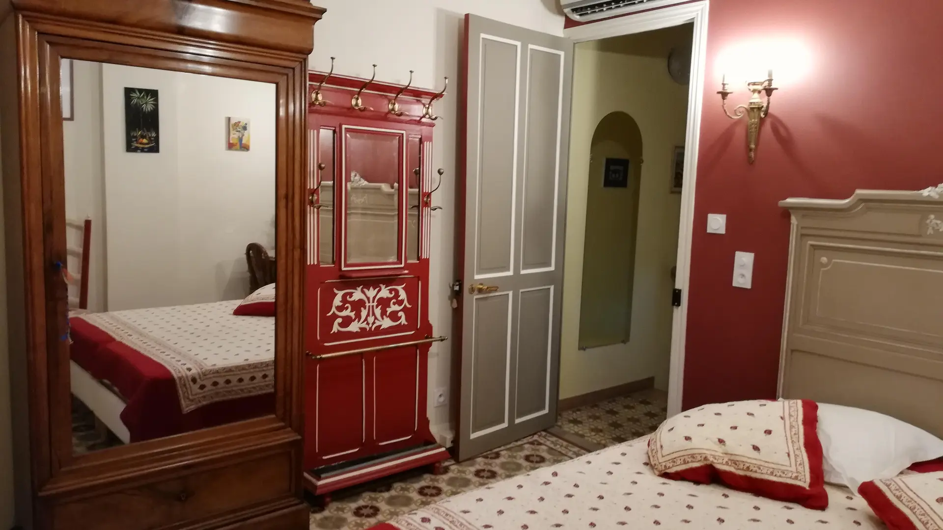 Une chambre spacieuse aux tons rouges et crème, alliant mobilier ancien et confort moderne.