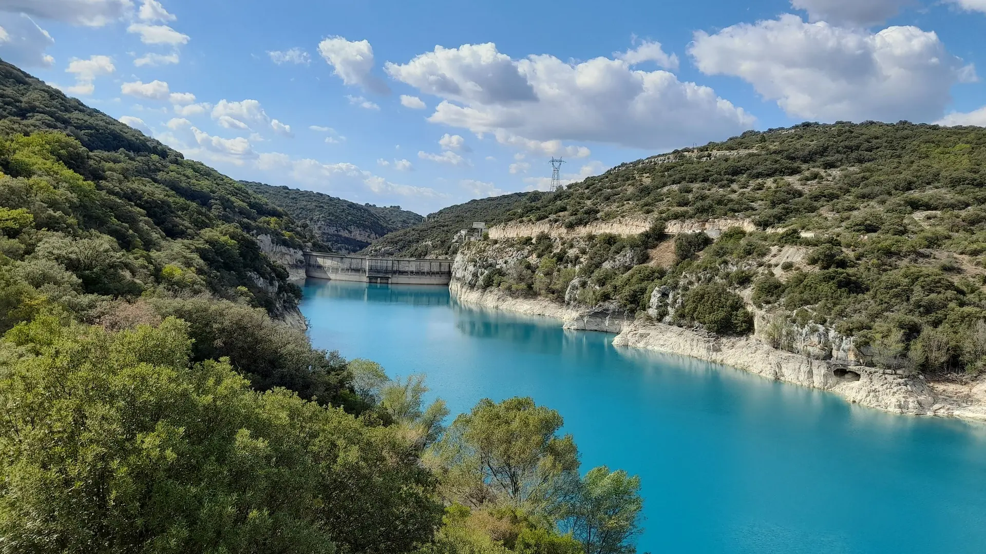 Vue sur le barrage, les berges calcaire et les eaux turquoises du lac entouré de végétation méditerranéenne