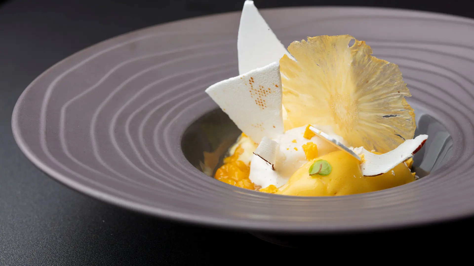 Un dessert sucré à base d'ananas, avec des éléments légers et aériens comme de la meringue. La présentation est épurée, mettant en valeur les couleurs vives du fruit.