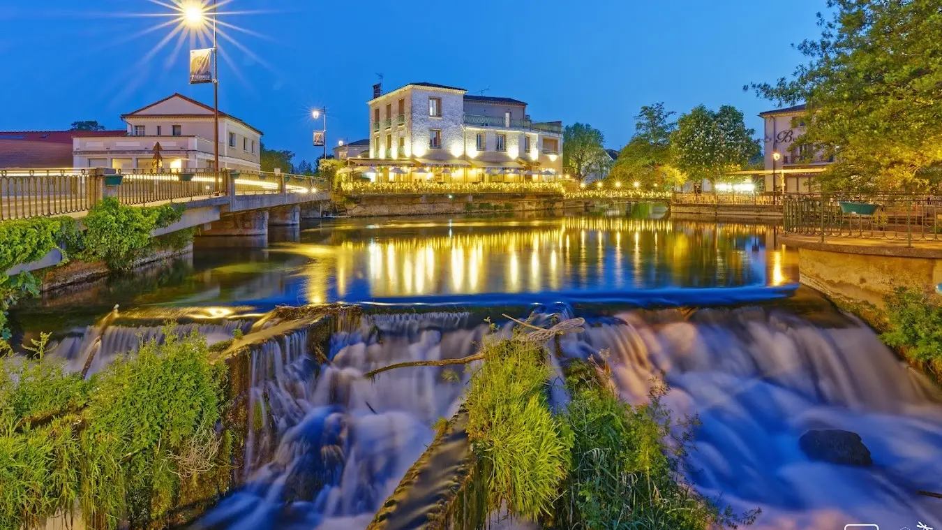 Vue sur la sorgue et l'hôtel du Bassin à la tombée de la nuit avec éclairage