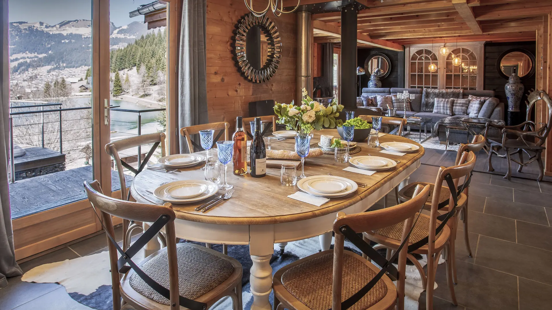 Salle à manger avec grande table, portes fenêtres donnant sur le balcon, vue sur les montagnes et vallée