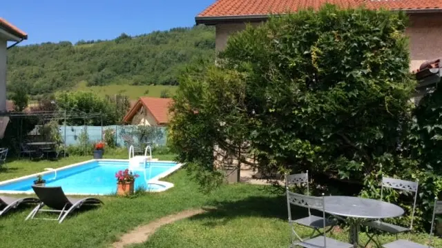 Un espace extérieur aménagé avec une piscine, une pelouse, quelques arbres et un salon de jardin.