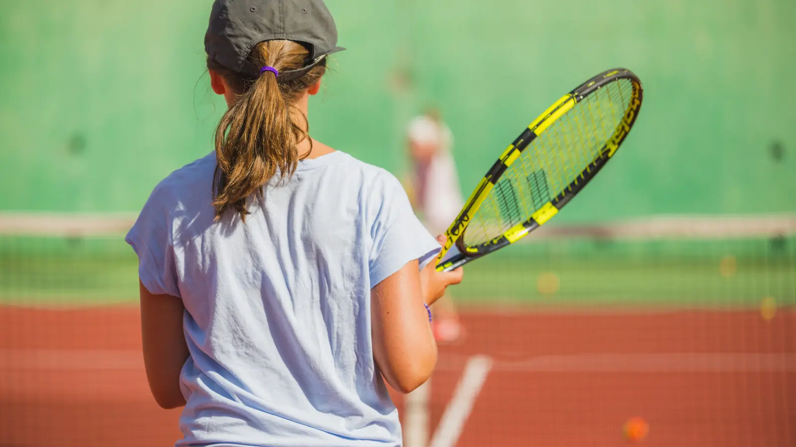 photo d'une jeune de dos tenant une raquette de tennis