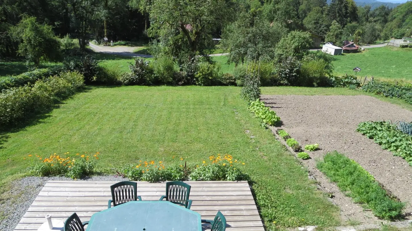 vaste terrasse en bois et jardin clos exposés sud jouxtant le potager des propriétaires.