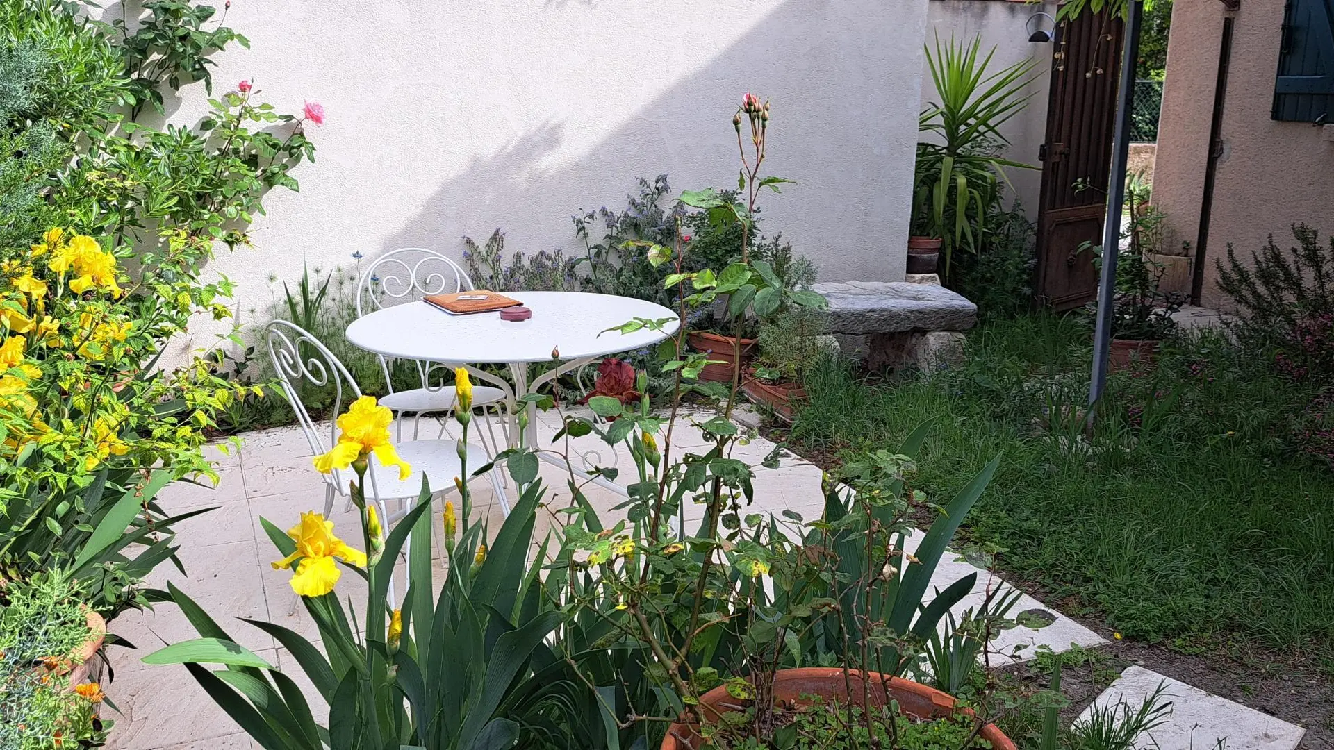 Terrasse jardin en fleurs dans la cour de l'Oustau dei Aucèus.