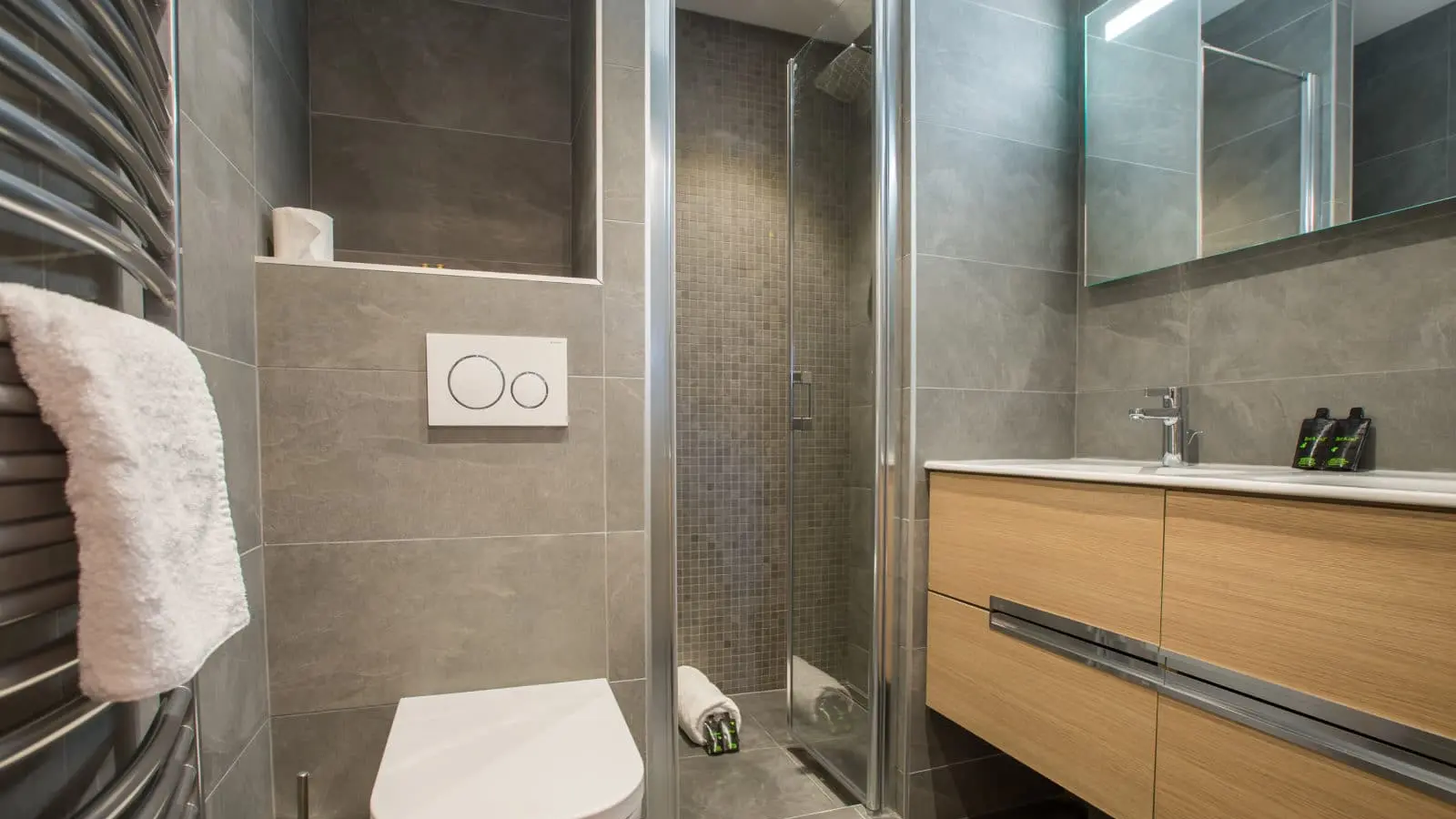 Salle d'eau avec douche à l'italienne, wc et vasque suspendu, matériaux contemporains gris et bois