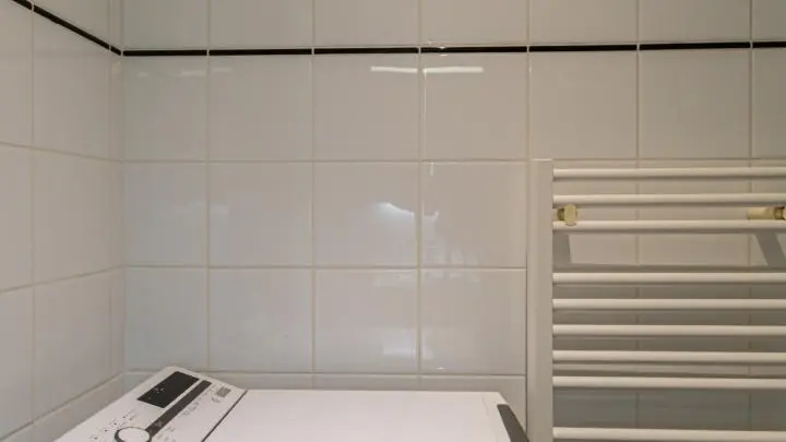 Lave-linge derrière la porte de la salle de bain.
