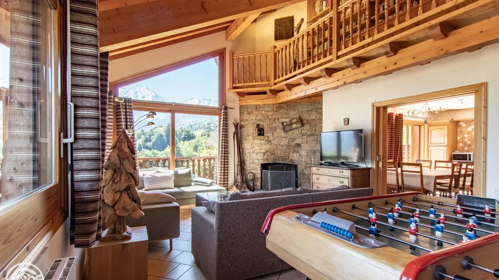 Salon et cheminée en pierres sèches. 2 canapés 3p et 2 fauteuils. Baby foot. Face au Mont-Blanc et aux Fiz.