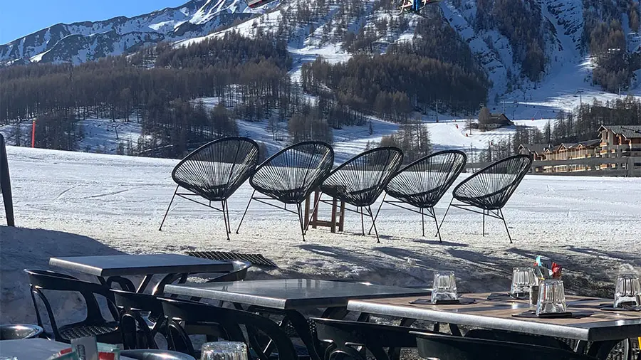 Vue des pistes de ski et des montagnes depuis la terrasse ensoleillée de l'établissement, télésiège à proximité