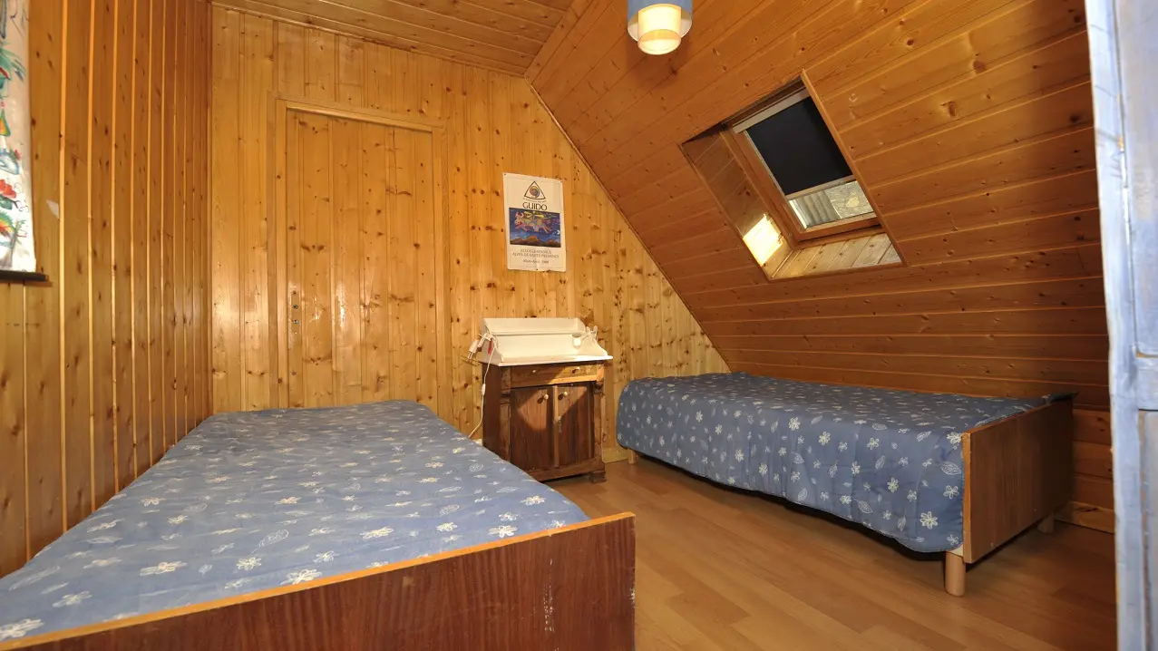 Bright attic bedroom with two single beds, skylight, wooden furniture, wood interior