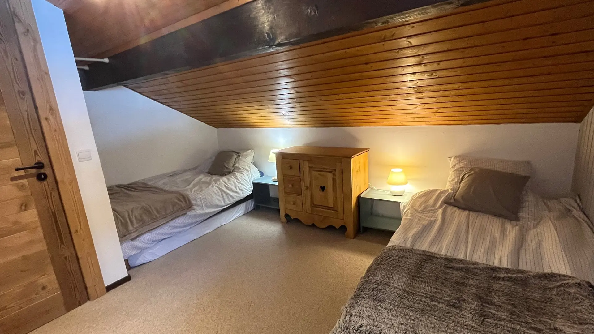 Chambre mansardée avec deux lits simples, commode et chevets