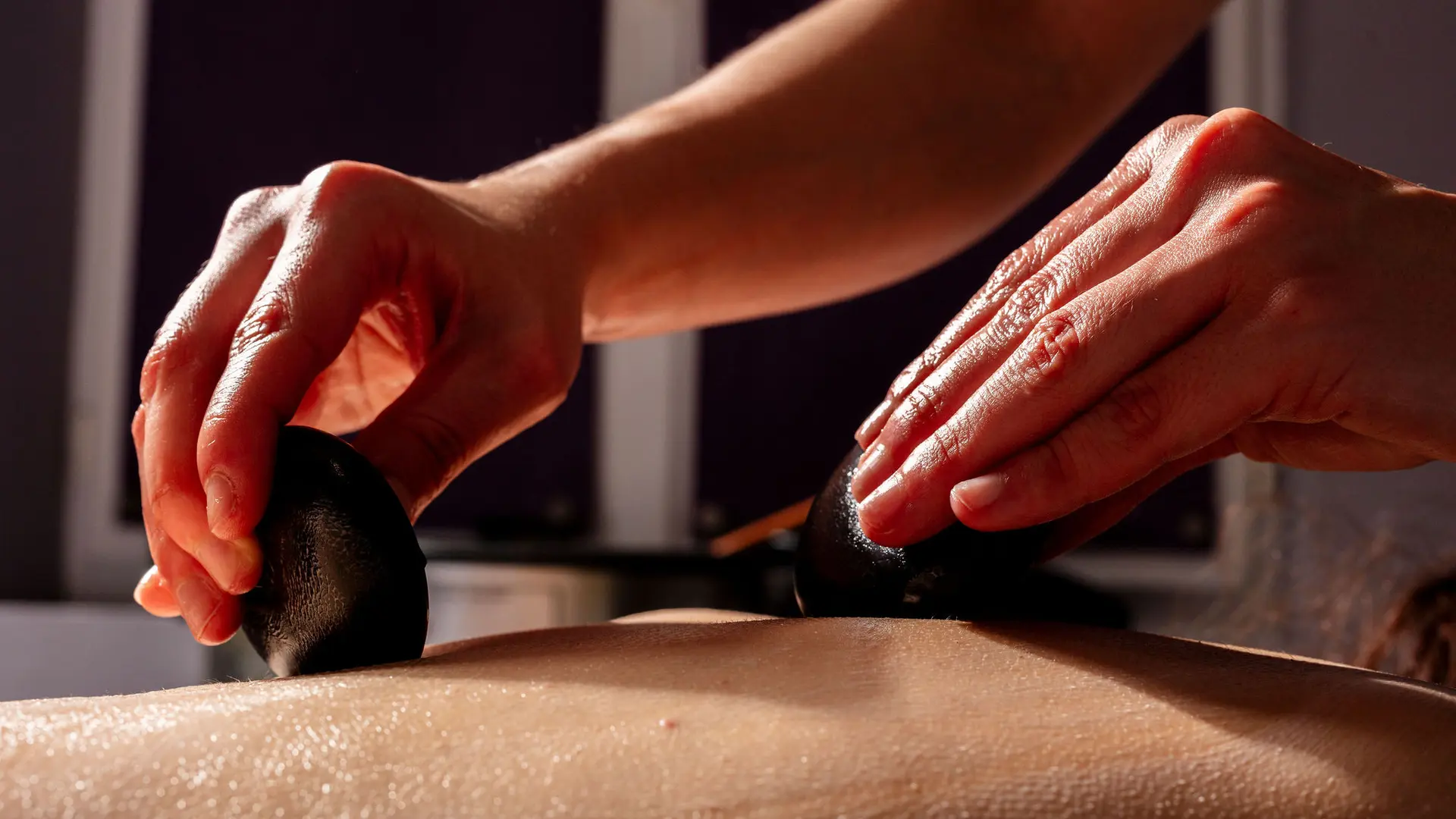 Une femme se fait poser des pierres chaudes sur le dos.