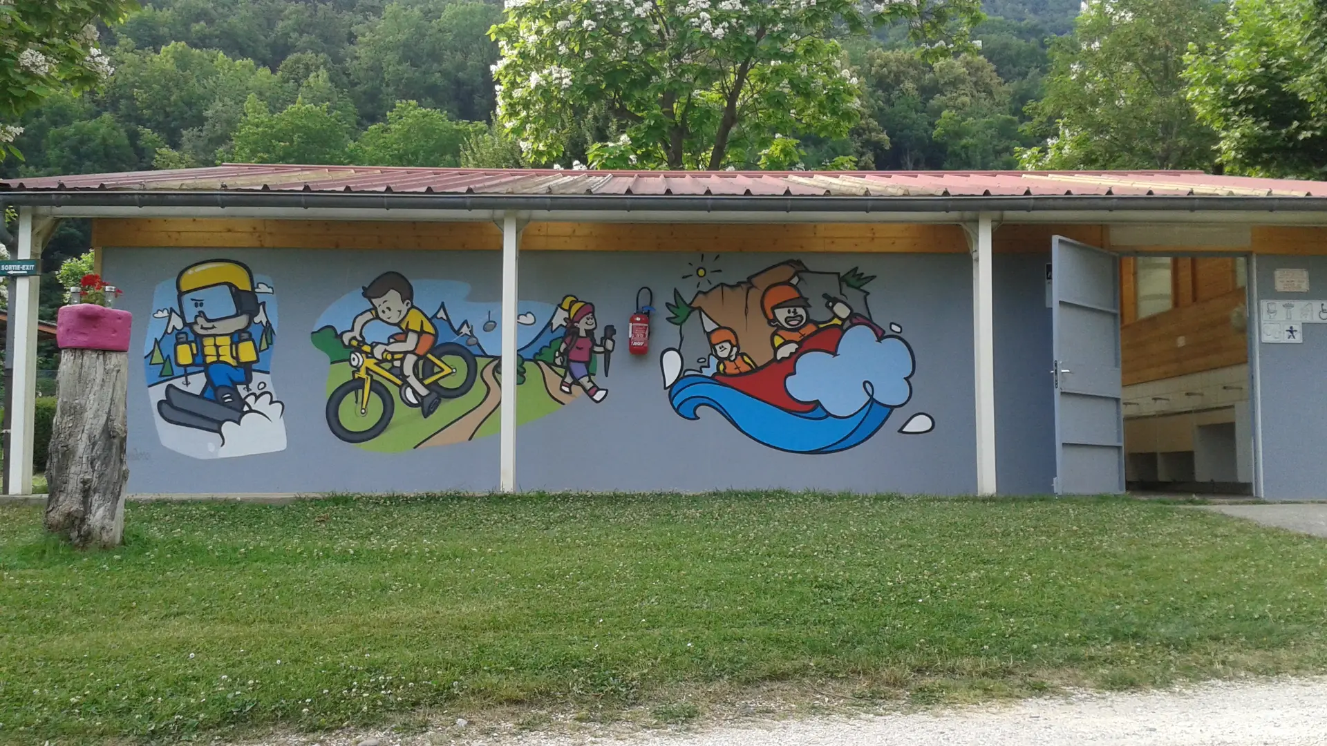 Le bâtiment des sanitaires présente un mur extérieur décoré de graffitis colorés et est abrité par un toit.