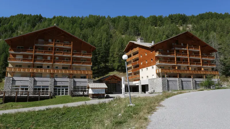View of the residence: two multi-story buildings connected by a central wing with a reception area, mountain setting