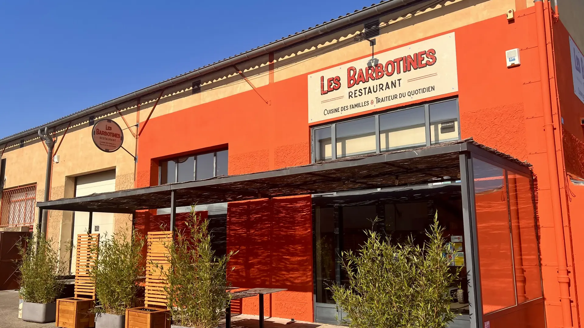 Façade du restaurant Les Barbotines, reconnaissable à sa couleur orange vive et sa terrasse accueillante.