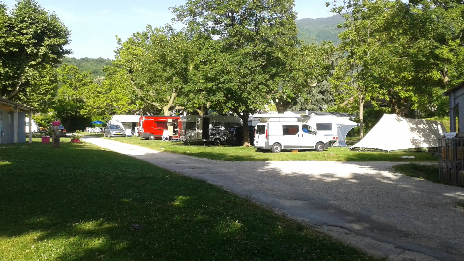 Les emplacements de camping sont aménagés sur un terrain herbeux et ombragés, bordé d'arbres, et desservis par un chemin de terre.