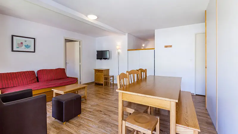Séjour lumineux d'appartement avec canapé, fauteuil, table à manger, TV, séparations vers autres espaces