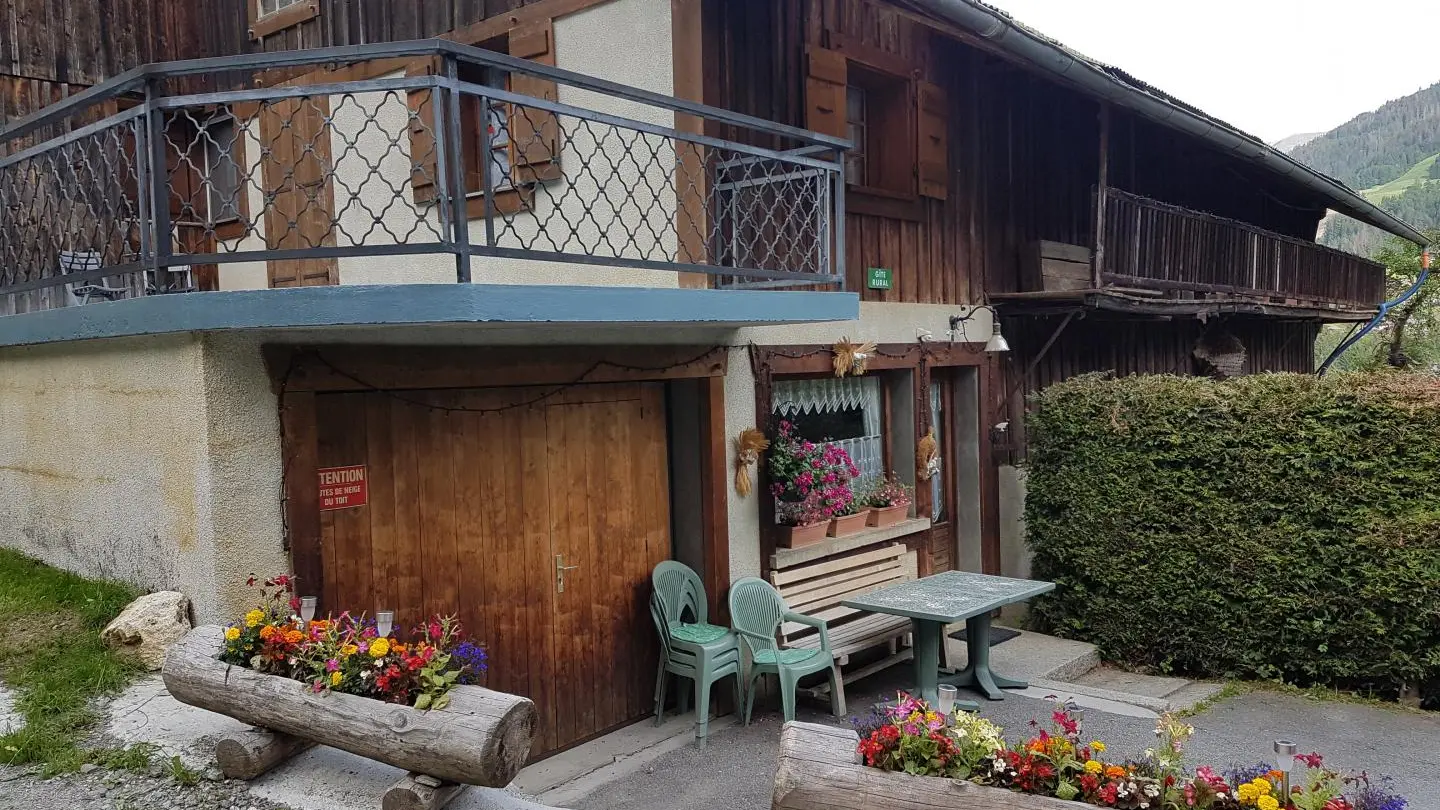 le gite et son garage et au dessus une grande terrasse avec une petite table ronde et 2 chaises.