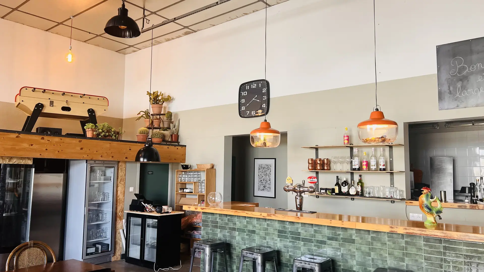 Intérieur chaleureux du restaurant avec bar, tables en bois et décoration conviviale.