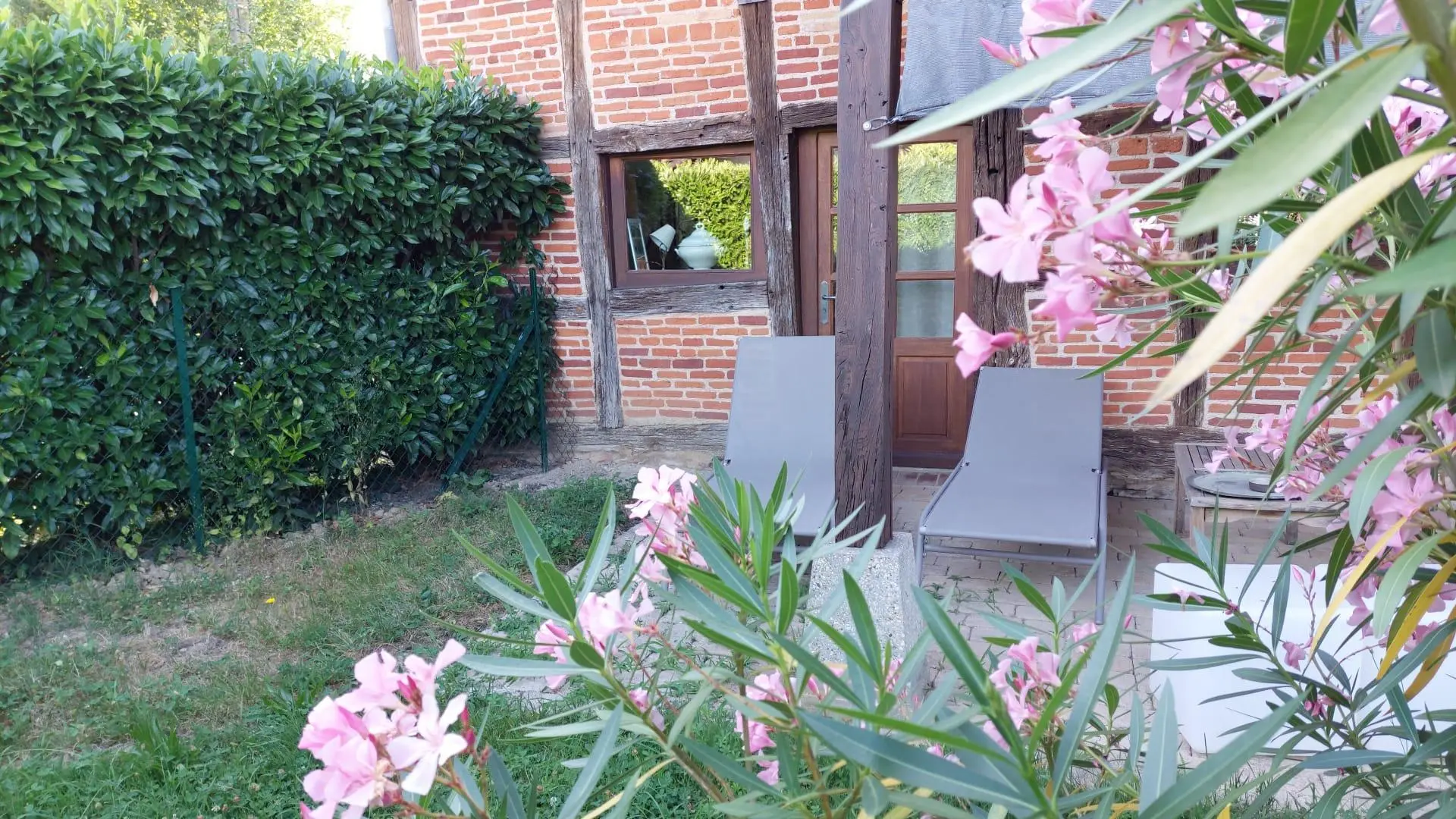 Terrasse couverte à l'arrière de la maison donnant sur un jardin clos
