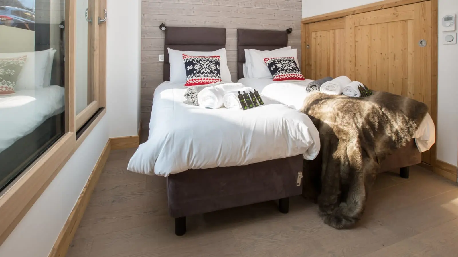 Chambre deux lits simples, décoration typiquement savoyarde avec du bois et des draps au motif de la montagne