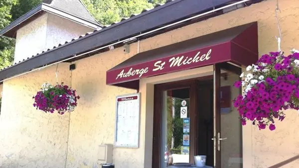 Ce restaurant possède une façade de couleur pastel. Une porte d'entrée, surmontée d'une marquise, est encadrée de deux fenêtres. Des plantes en pots décorent l'entrée.