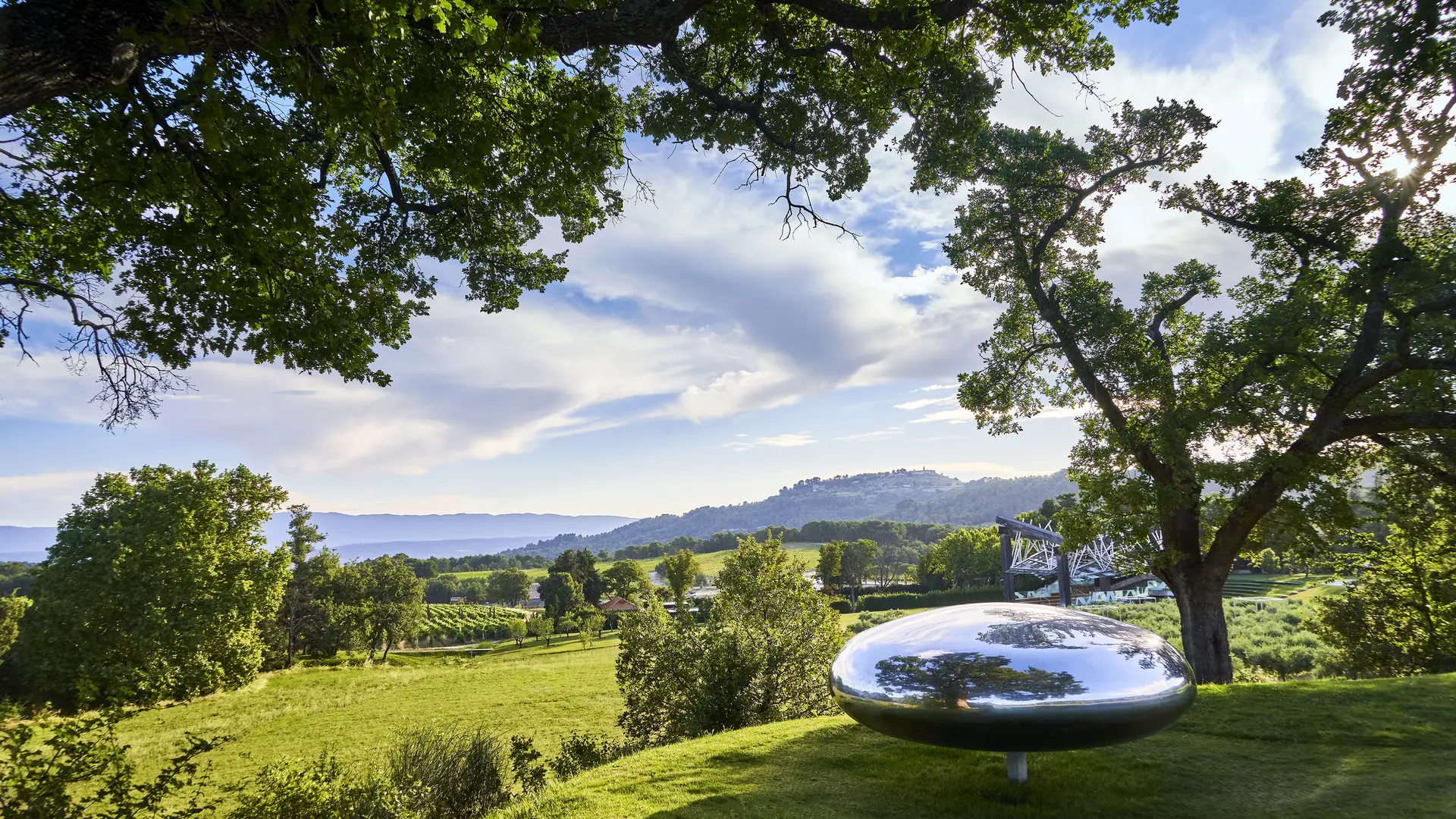 A polished steel sculpture that turns and tilts when pushed, then returns to rest. Tom Shannon, Drop, Château La Coste. Photo © Richard Haughton