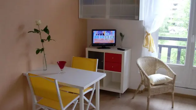 Le studio est équipé d'une table de salle à manger avec deux chaises, d'un meuble TV avec un téléviseur, d'un fauteuil et d'une fenêtre donnant sur le Parc d’Uriage.