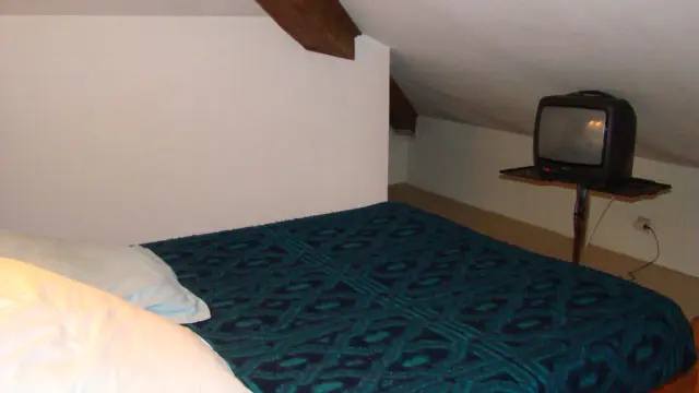 Chambre à coucher sous combles avec lit double, TV, ameublement bois