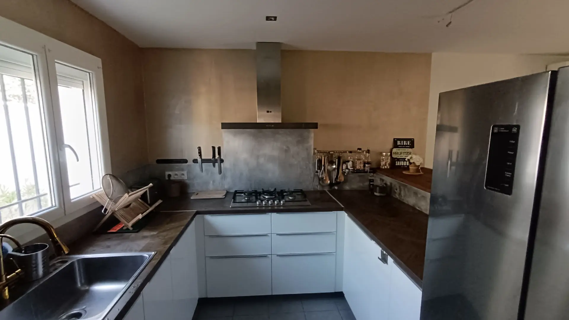 Cuisine moderne toute équipée avec évier, four, micro-ondes, lave-vaisselle et nombreux rangements.