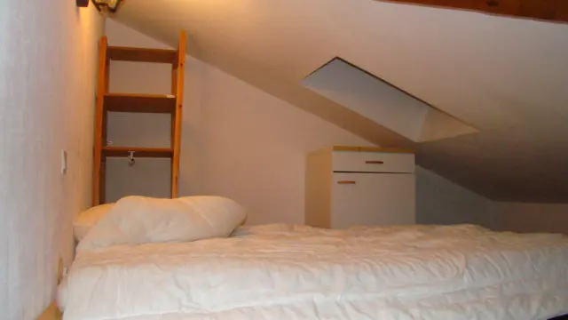 Chambre à coucher sous combles avec lit double, ameublement bois, espace de rangement