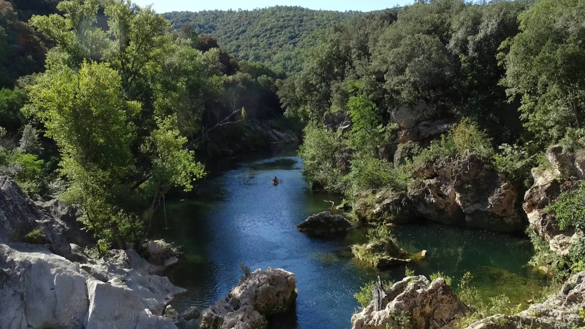 Vue sur la rivière entourée de rochers blancs et de végétation verdoyante