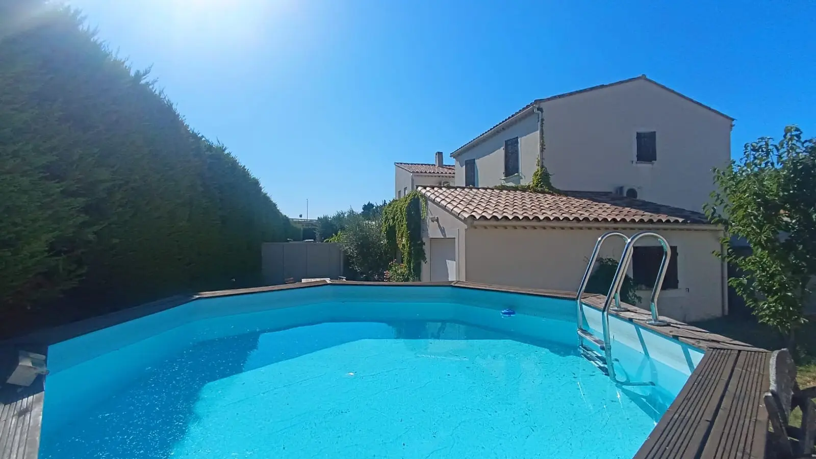 Piscine hors-sol avec terrasse bois et échelle sécurisée, idéale pour profiter du soleil.