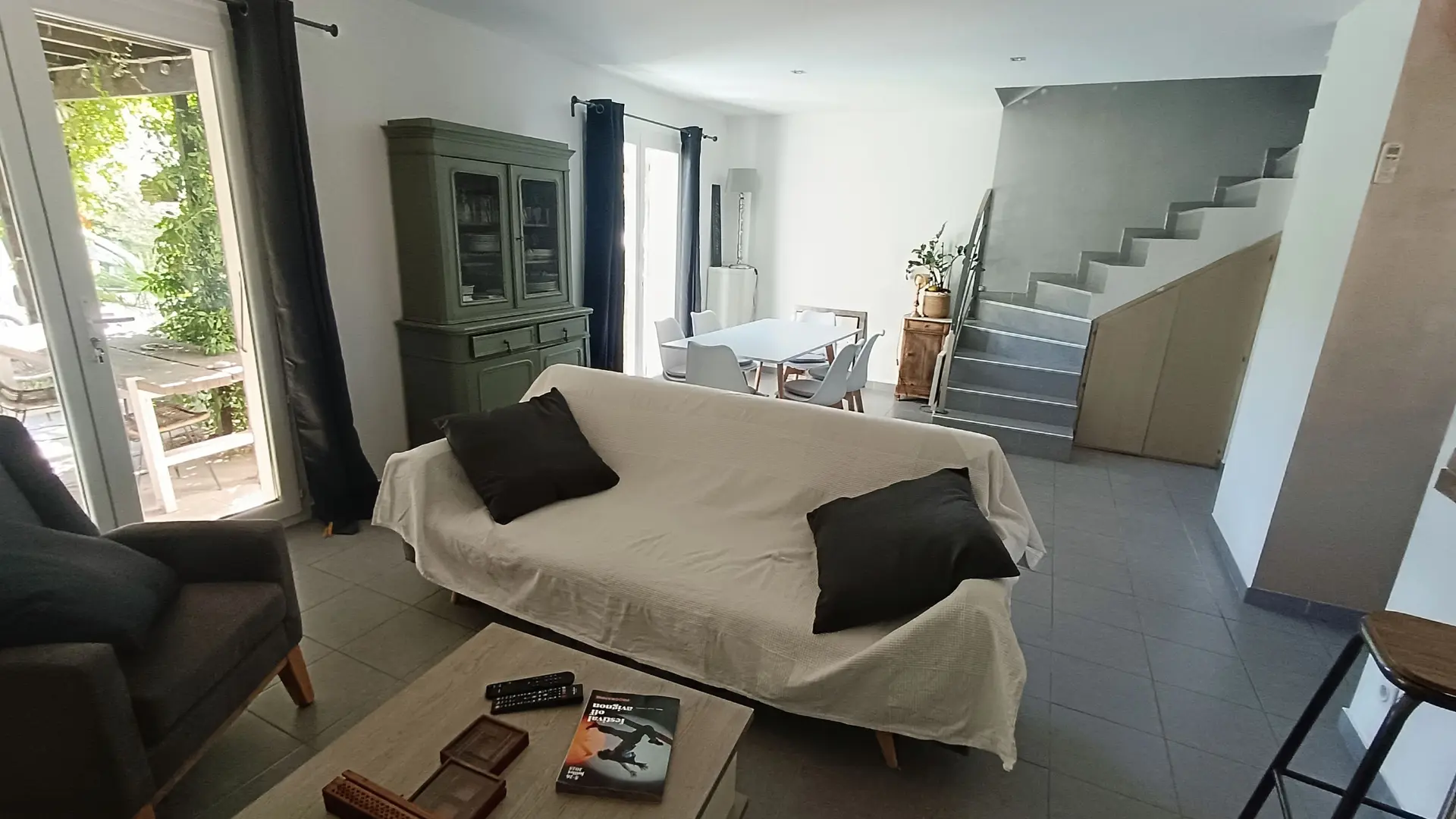 Salon convivial avec canapé, fauteuil, table basse et accès direct à la terrasse.