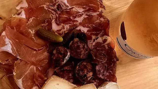 Planche à découper en forme d'île de Corse avec charcuterie, fromage, olive et basilic