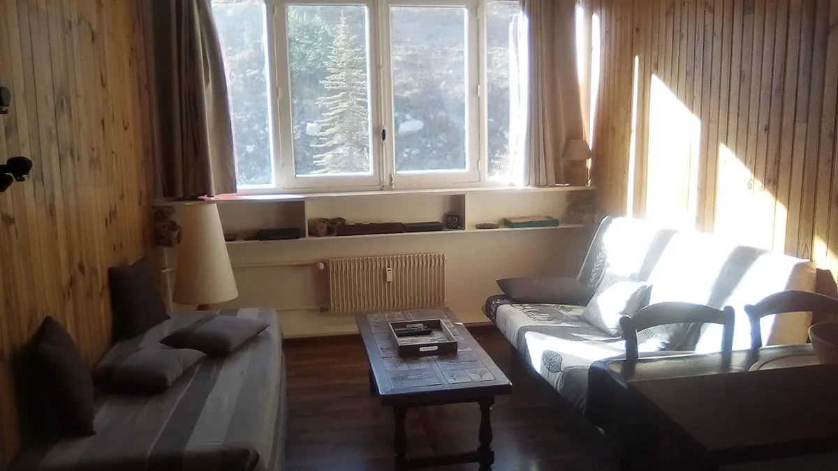 Séjour lumineux ameublement bois, lambris, fenêtre et rideaux