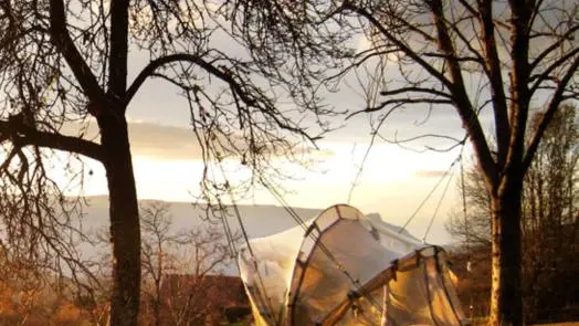 Tente suspendue dans les arbres au soleil couchant ave vue sur le Vercors.