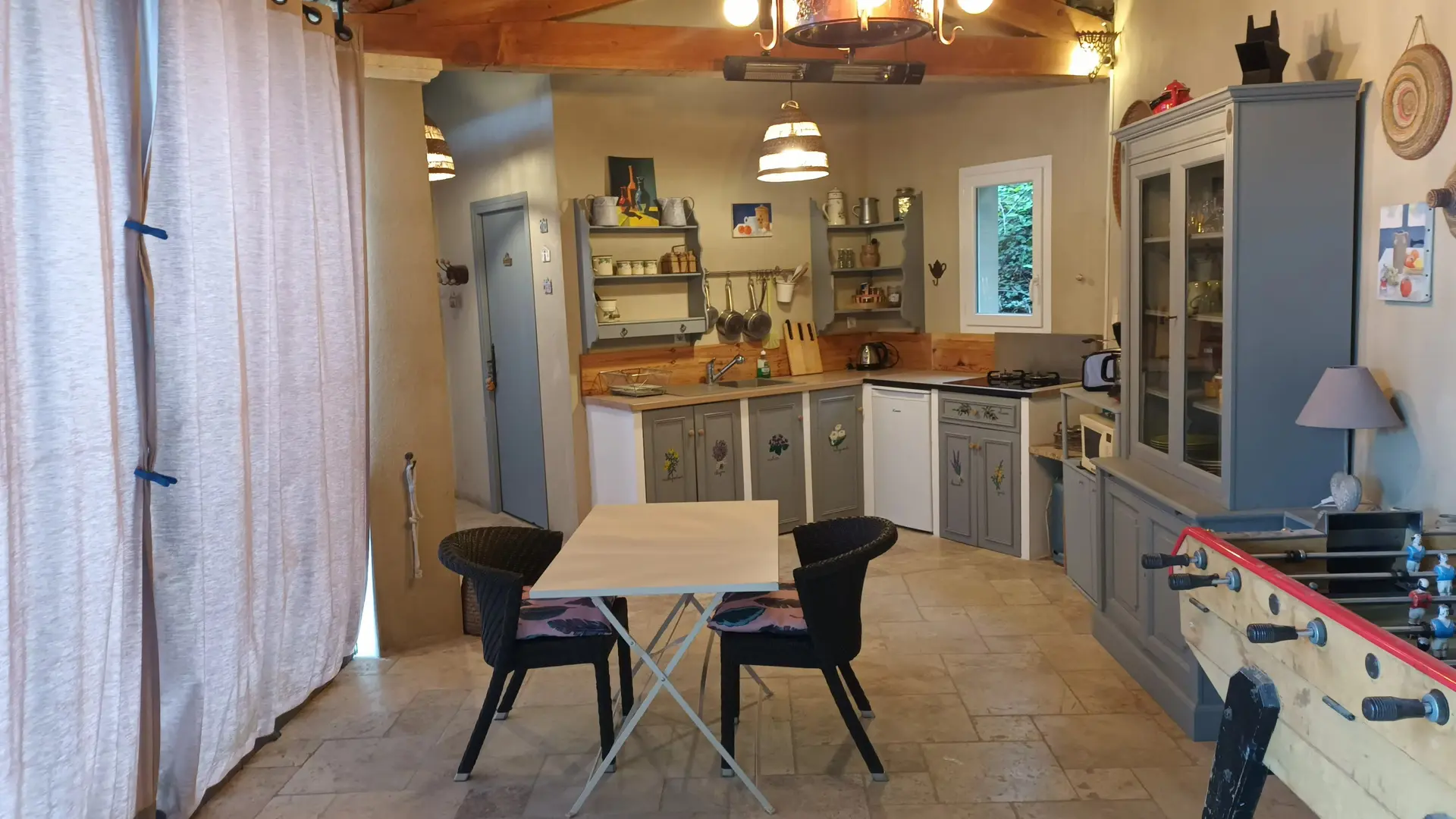 Vue de la cuisine et coin repas sous le auvent protégé par des rideaux déperlants