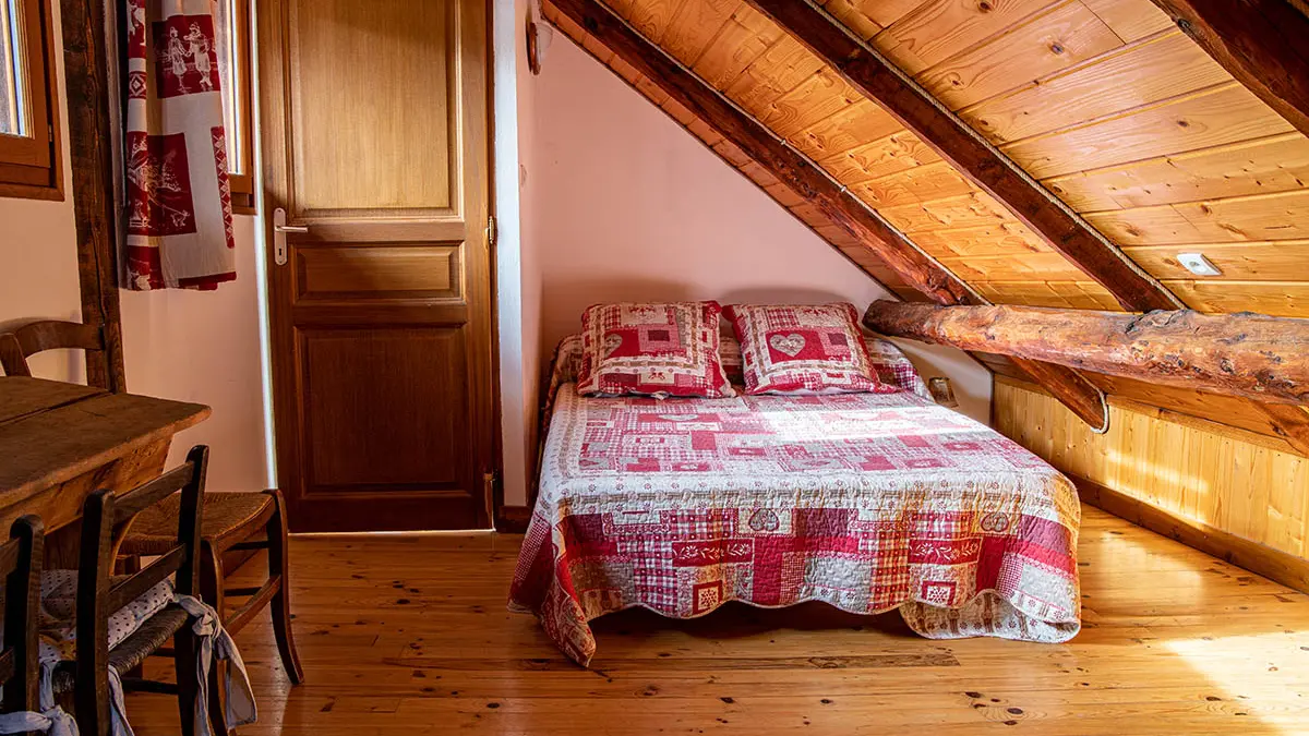 Bright attic bedroom with double bed, wooden furniture and window