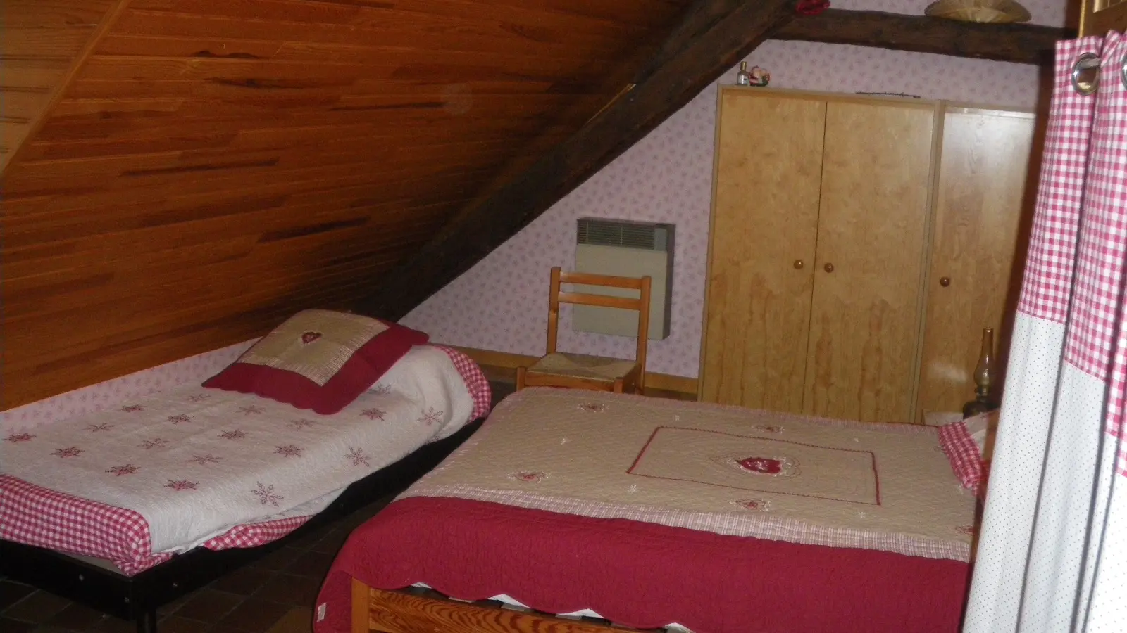 Chambre à coucher sous combles avec lit double, lit simple, ameublement bois, sol carrelé