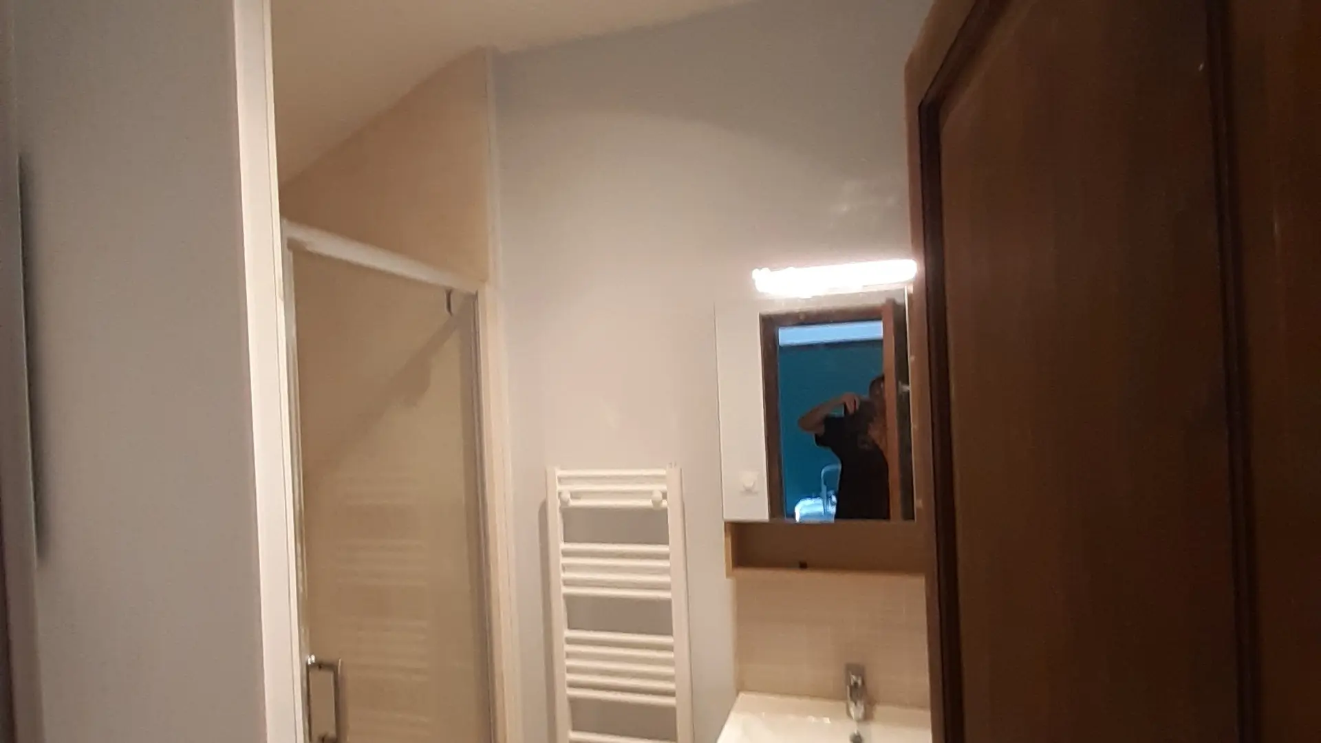 En entrant, vous trouverez à gauche une douche, puis un lavabo avec un miroir et un sèche-serviettes sur le mur de droite.