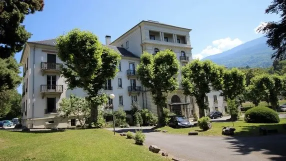 Ce bâtiment de style classique est situé dans un environnement verdoyant.