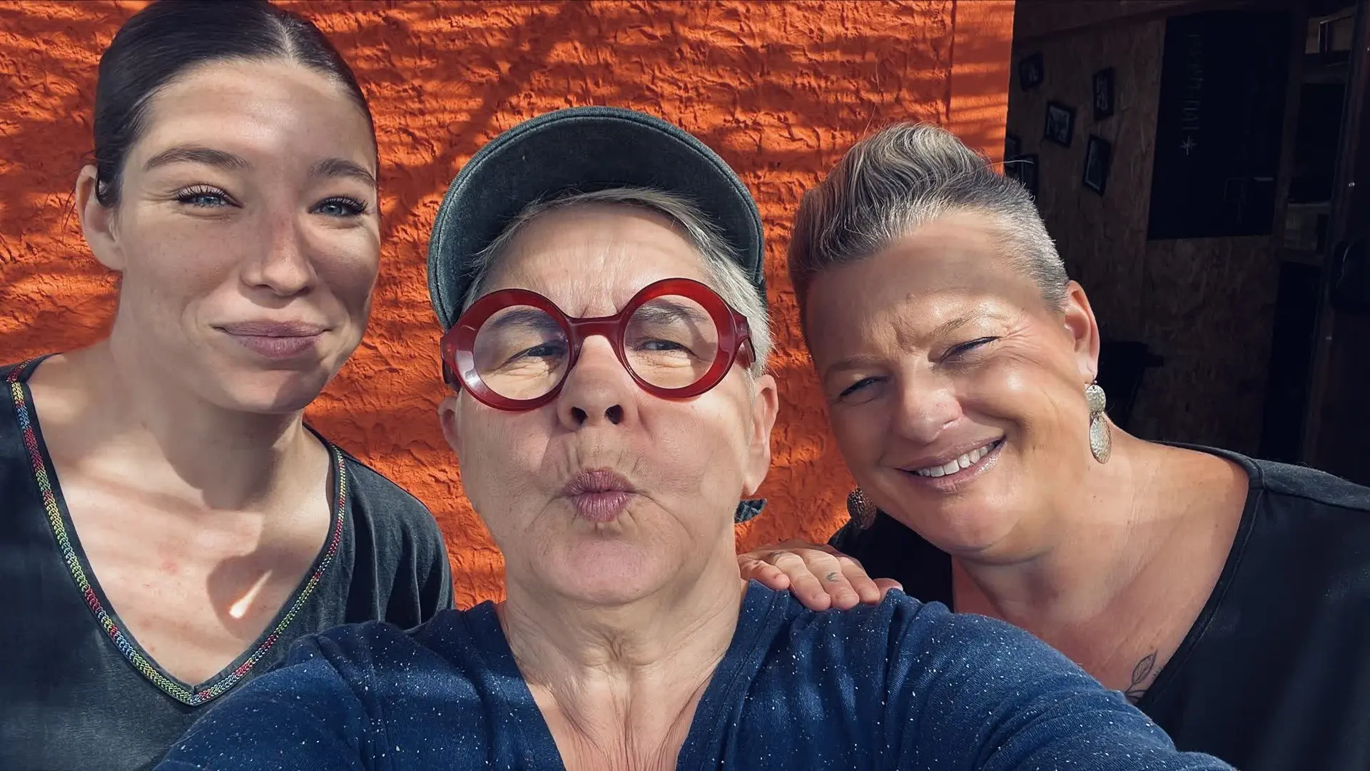 Portrait souriant de l’équipe du restaurant devant le mur orange.