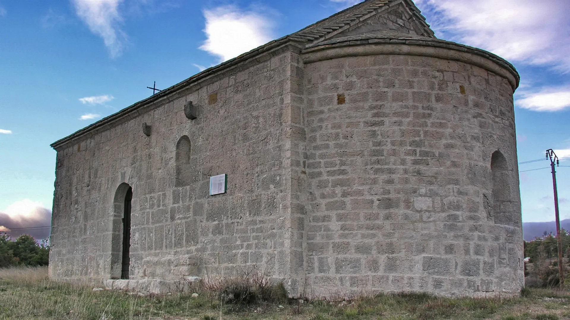 Vue sur l'arrière de la chapelle en pierre avec une petite croix en fer
